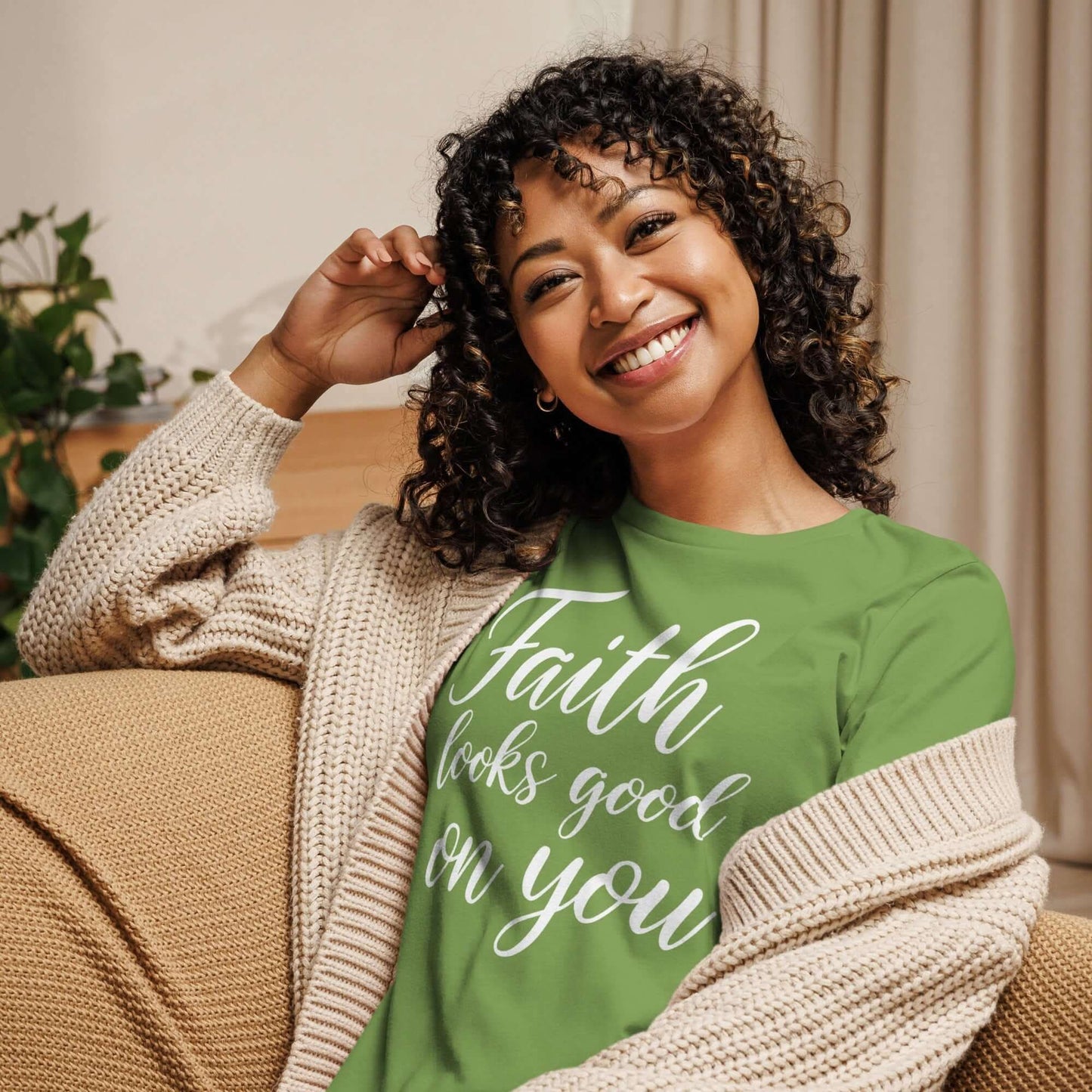 Woman smiling while wearing the Faith Looks Good on You Tee – White Cursive Edition, styled with a cozy cardigan.