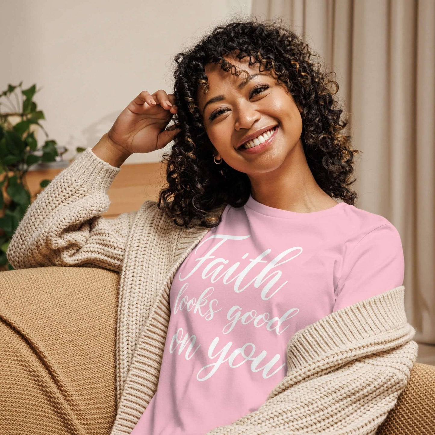 Smiling woman in a cozy setting wearing the Faith Looks Good on You Tee – White Cursive Edition.
