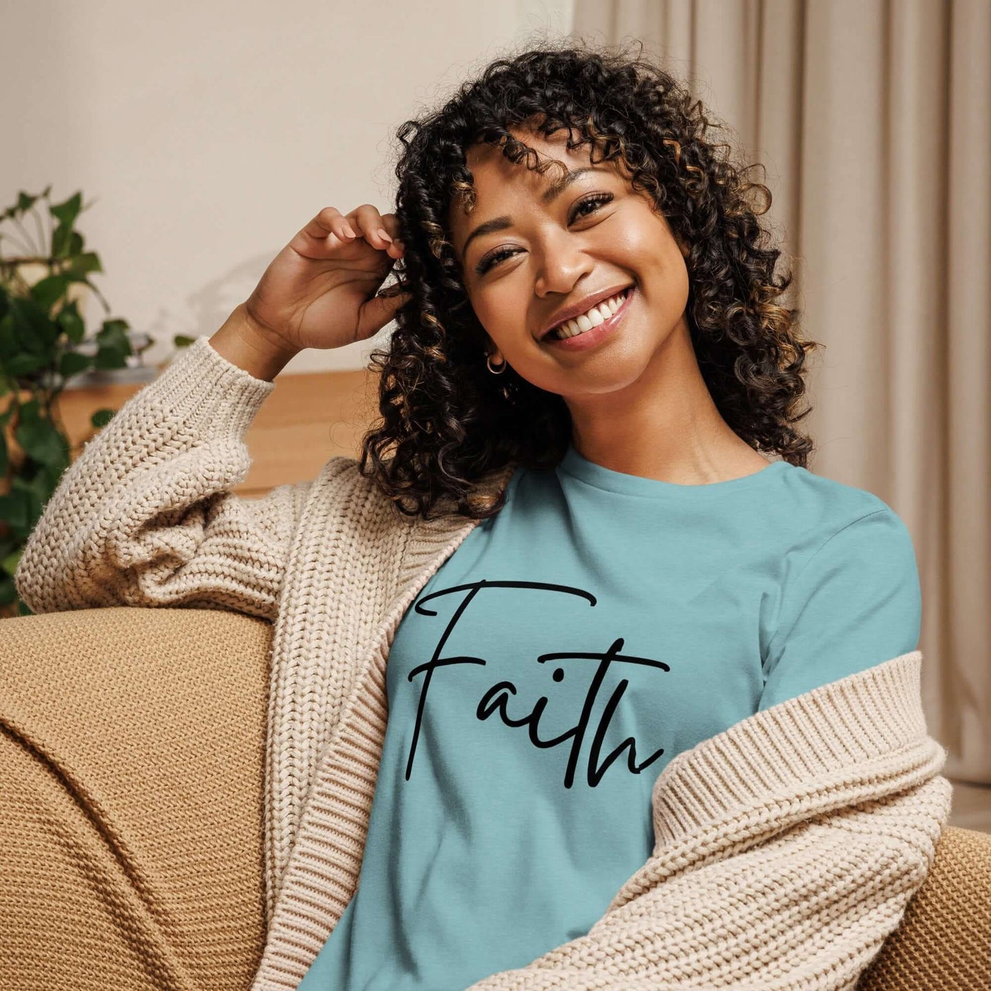 Smiling woman wearing a Faith tee in turquoise with black cursive lettering, showcasing style and positivity.