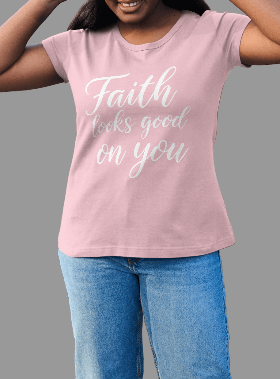 Woman wearing the Faith Looks Good on You Tee in pink with elegant cursive lettering.